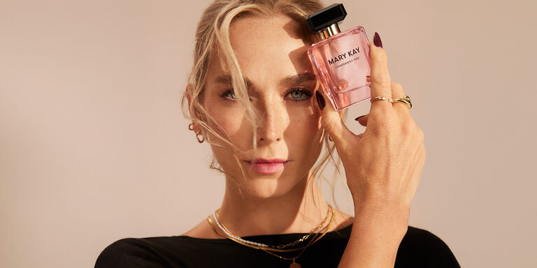 Model holding a bottle of Mary Kay Confidently You Eau de Parfum while looking at the camera